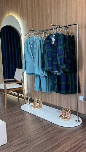 Clothing rack with jackets and plaid shirt against a wooden wall.